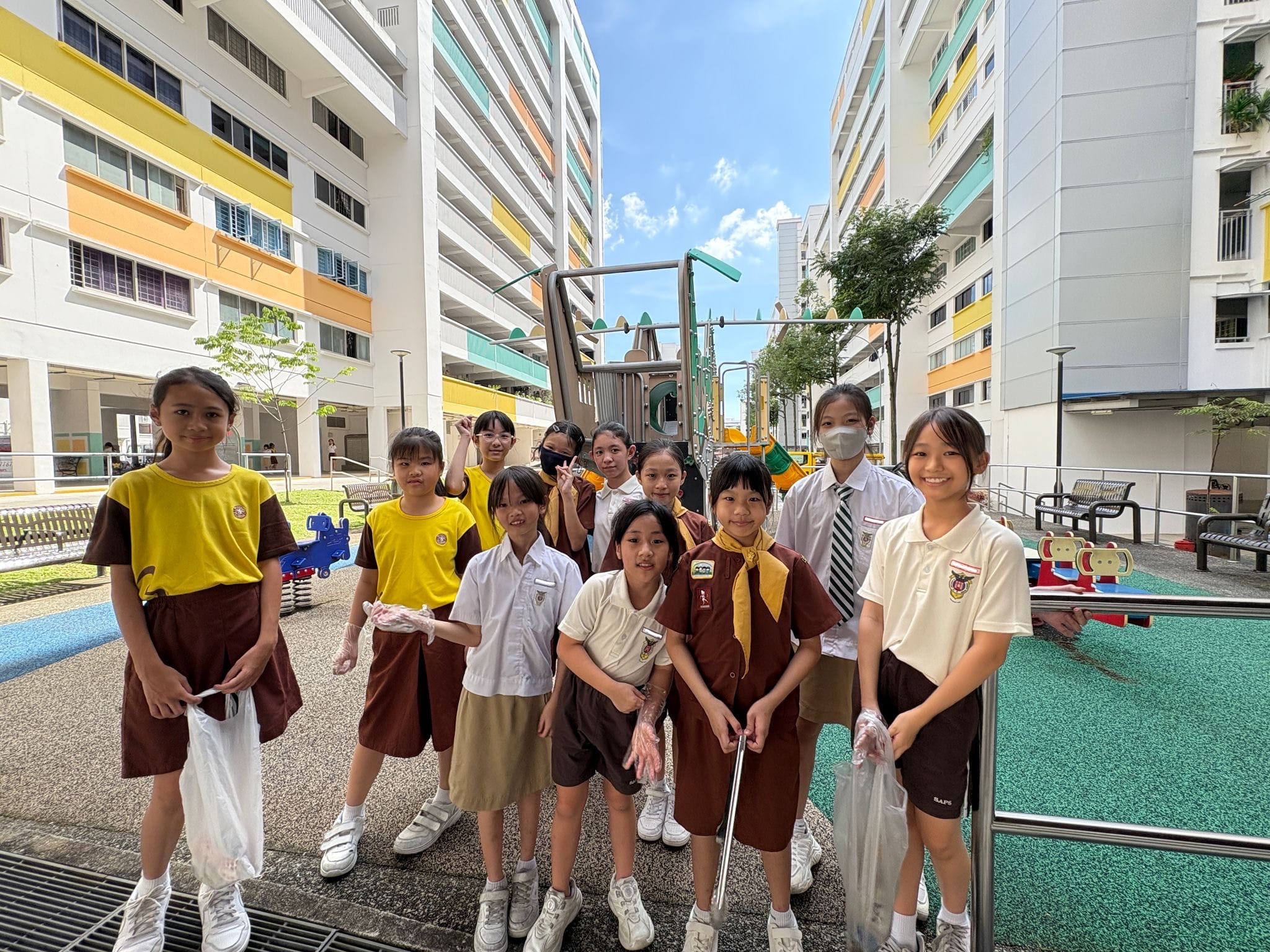 Singapore Brownie Girl Guides in brown uniforms play a colorful board game at a table during an event.